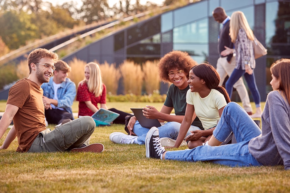 Diverse group of university students sitting on the lawn smiling