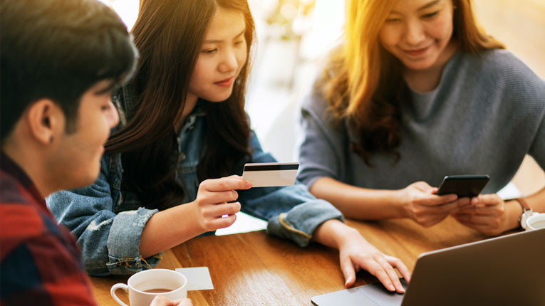 Group of asian young adults finding their first credit card disclosure by researching it online.