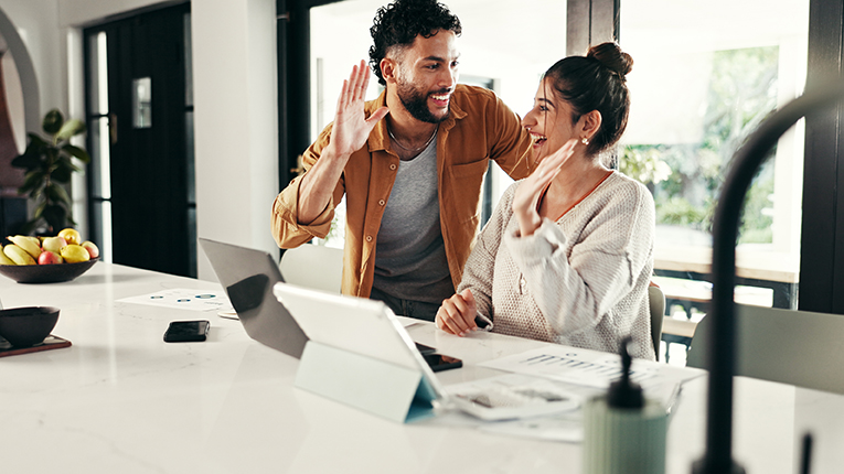 young happy couple high fiving in front of laptop