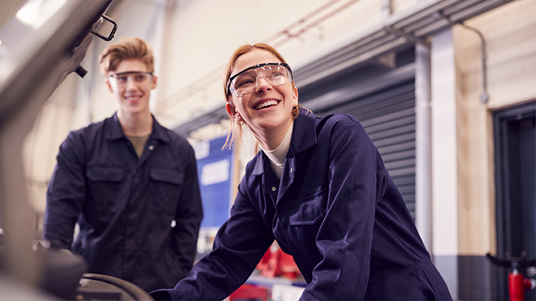 Male and female students looking at a car engine on auto mechanic apprenticeship course