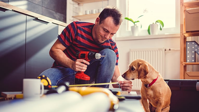 middle aged man doing home renovations with dog watching 
