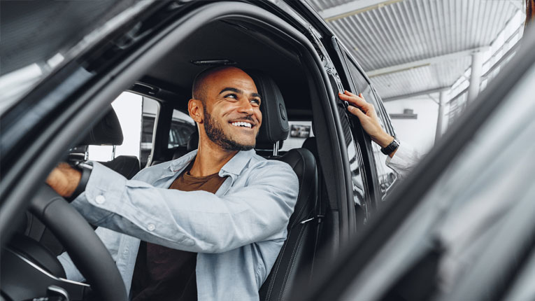 Man-smiling-in-his-new-car-after-discovering-what-credit-score-is-needed-to-buy-a-car-beacuse-he-qualified.