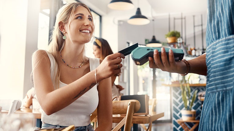 Shot of a young woman making a card payment using a nfc machine