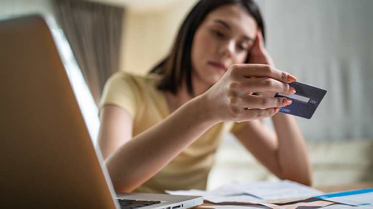 stressed young woman staring at her credit card