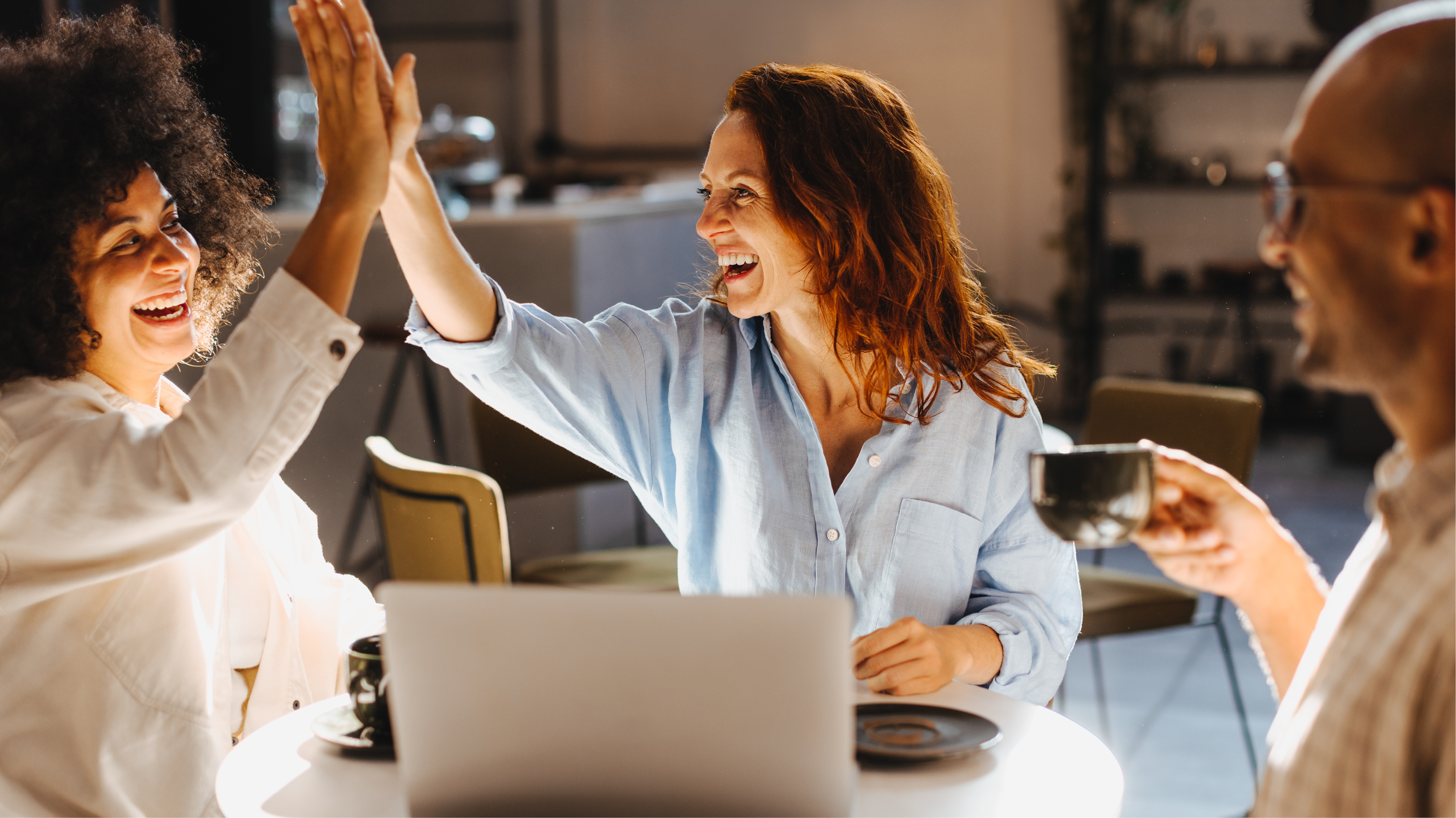 Successful business team high fiving in a coffee shop