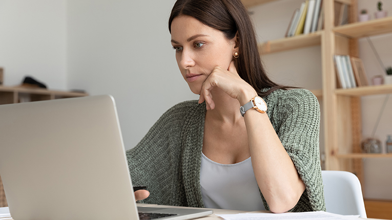 Thoughtful young businesswoman sitting at table with computer