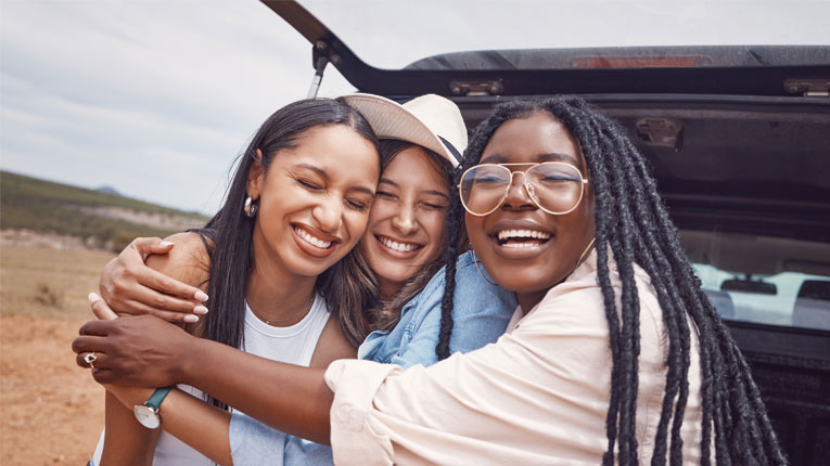 Three-friends-hugging-in-back-of-their-new-car-they-purchased-after-realizing-the-best-best-for-auto-loans-isnt-a-bank.