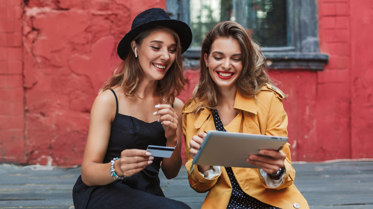 Two women researching how many credit cards should I have on a laptop.