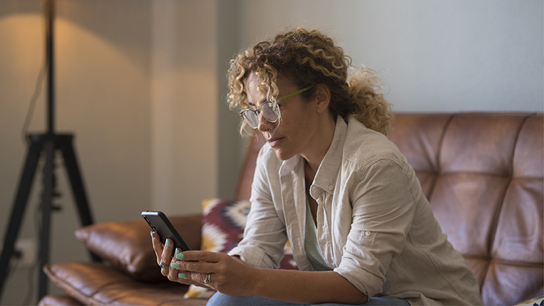 Serious young African American woman looking at text message on phone