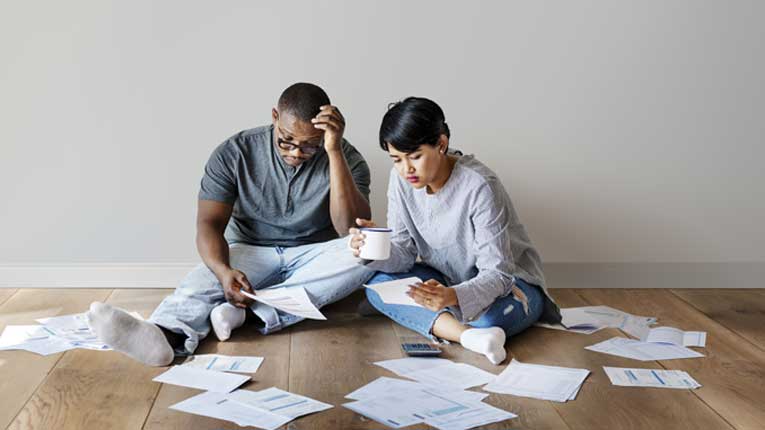 You can learn how to pay off credit card debt fast with peach state debt consolidation loans couple sitting on floor surrounded with bills.