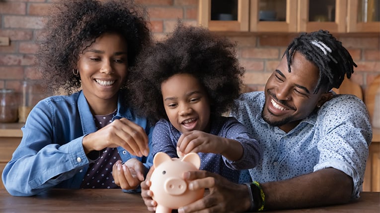 young girl and her parents save money in a piggy bank