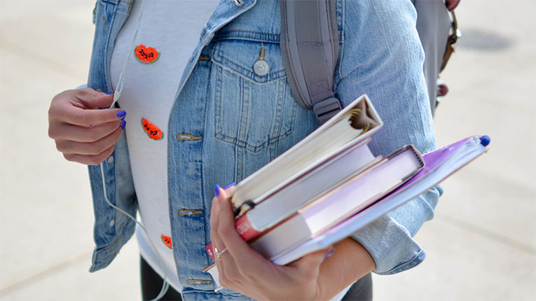 College-woman-carrying-her-books-in-her-arm.