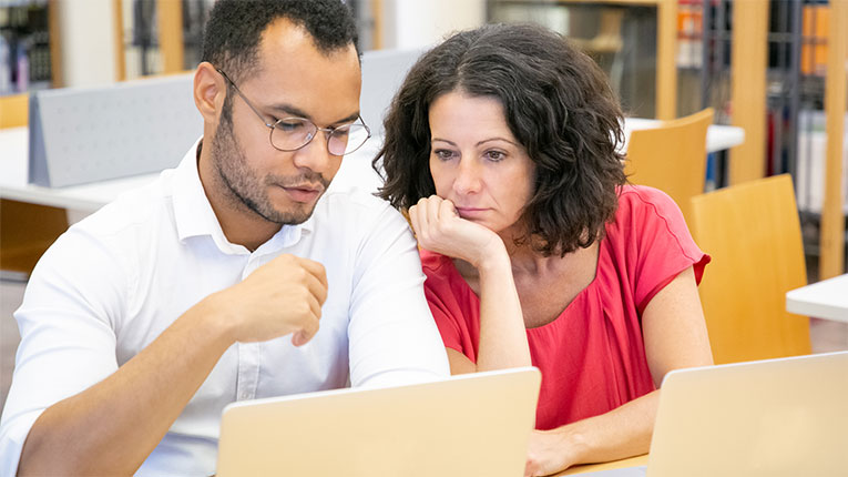 Couple at a laptop deciding if a personal loan vs payday loan is better for their needs.