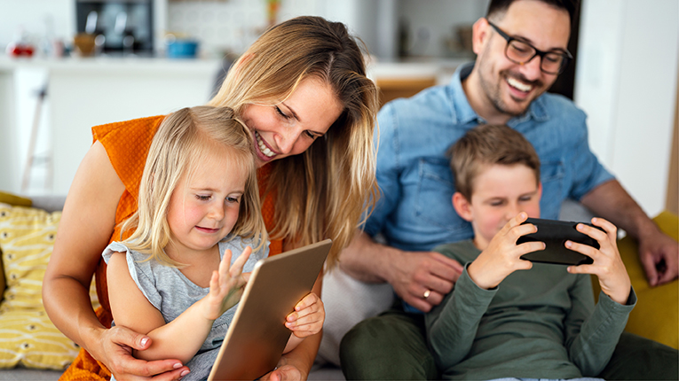 Happy young family having fun time at home. Parents with children using tablet