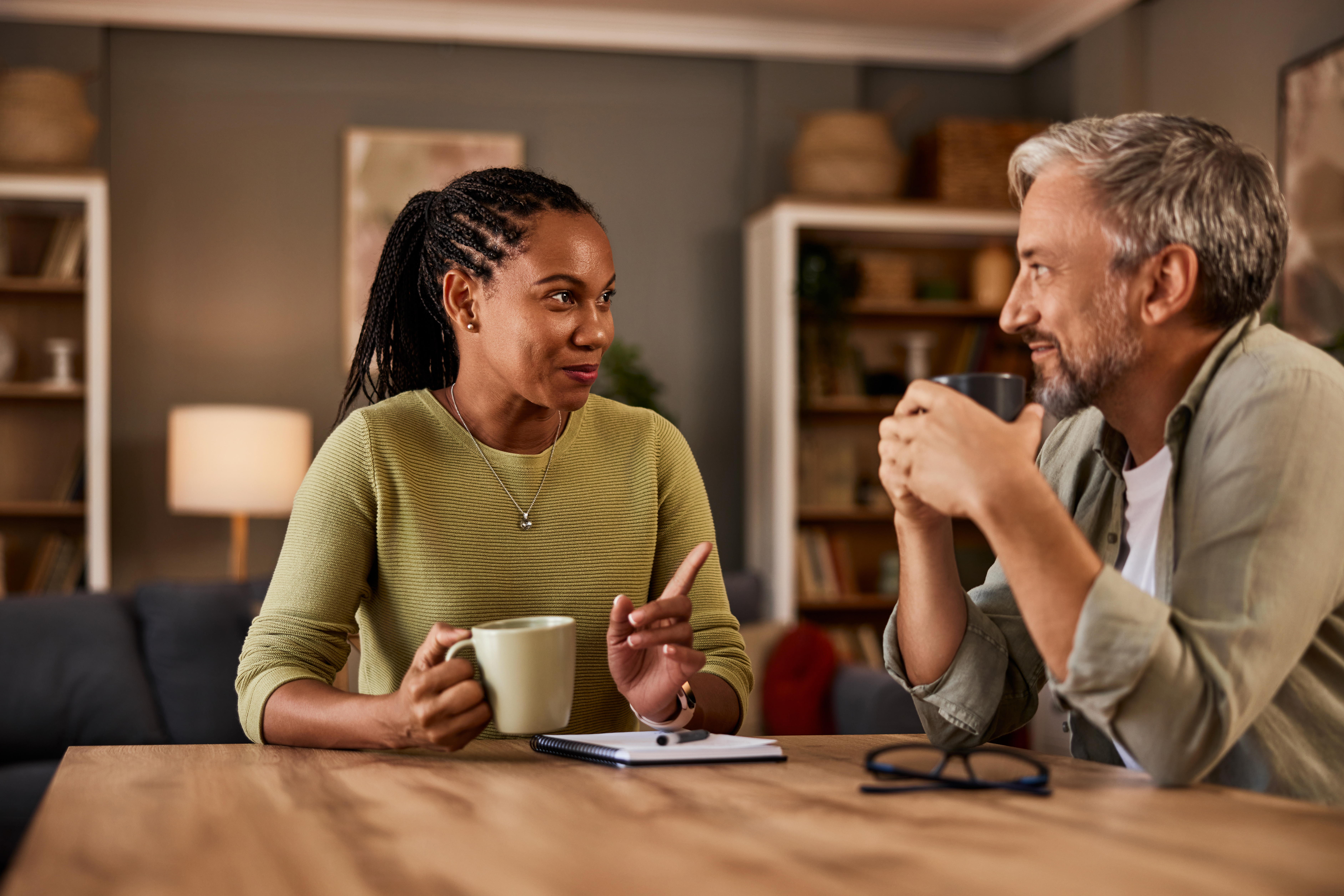 Mature couple talking while enjoying a hot drink at the table at home.