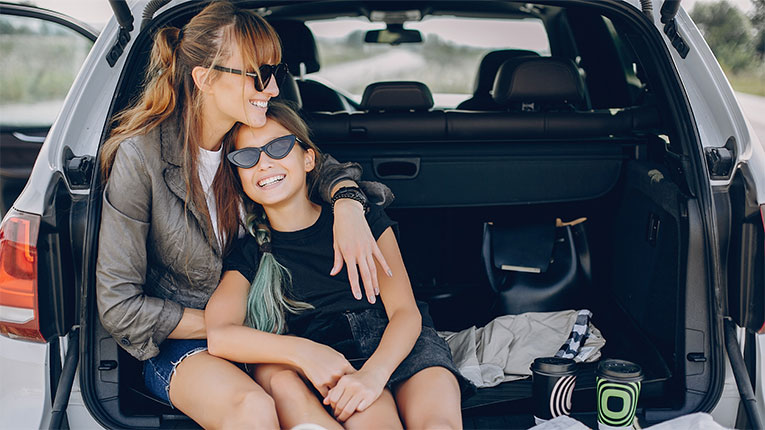 Mom-and-daughter-in-back-of-car-after-enjoying-a-rideafter-refinancing-and-saving.