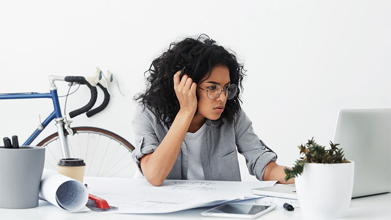 Woman confused why her credit scores are different as she reviews her credit report on her laptop.