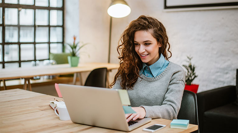 Woman-researching-car-loan-rates-on-her-laptop-at-her-desk.