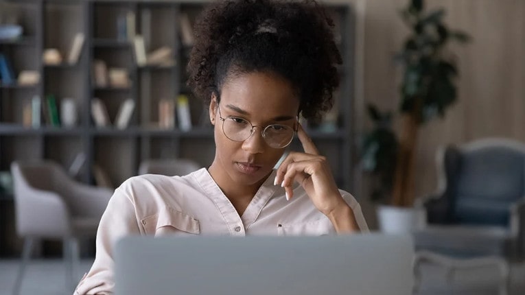 a woman protecting herself from fraud by researching online scams on her laptop