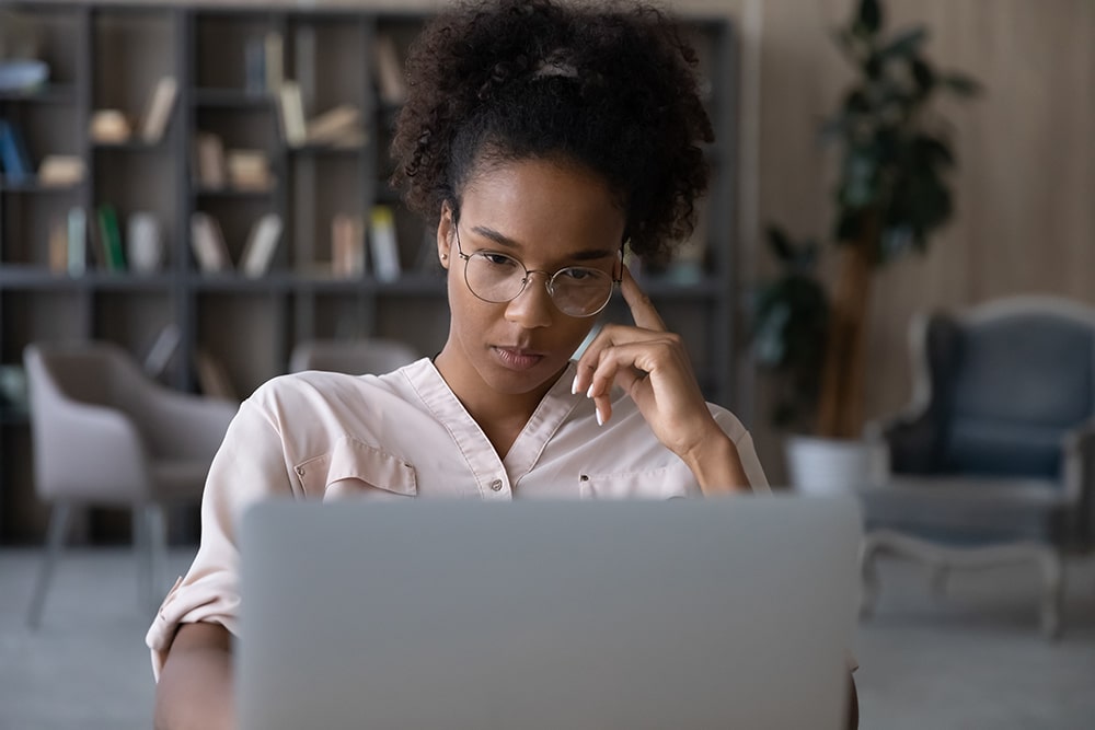 A woman protecting herself from fraud by researching online scams on her laptop. 