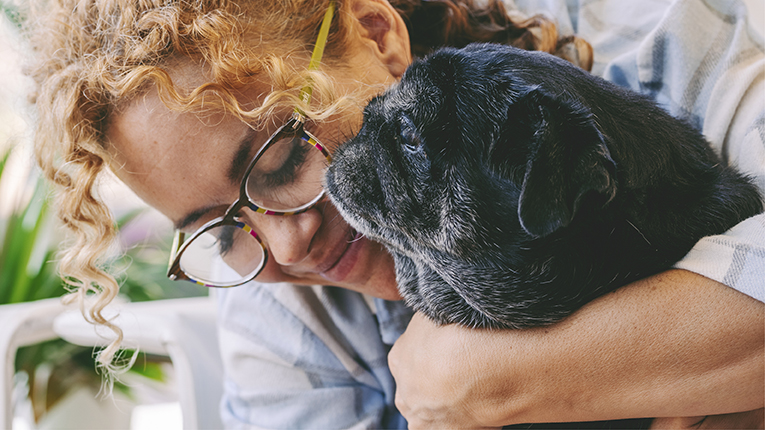 happy adult caucasian woman and black old pug hugging and loving with tendernes together