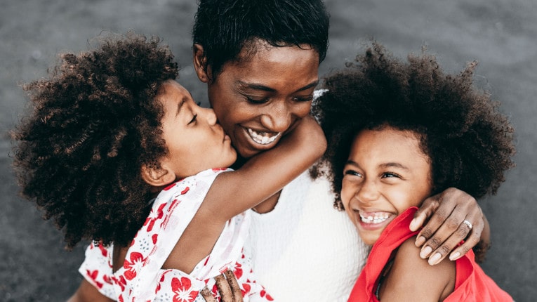 Mom hugging her daughters after feeling relief from a personal loan