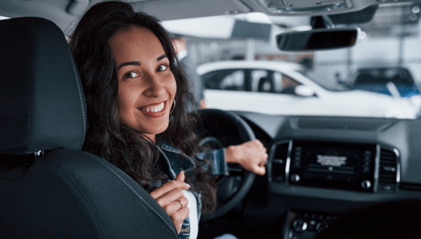 Woman backing up a car smiling.