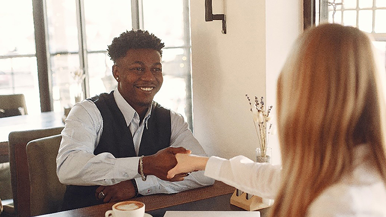 Young African American man interviewing with a woman shaking hands. 